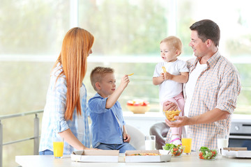 Happy family eating pizza in kitchen