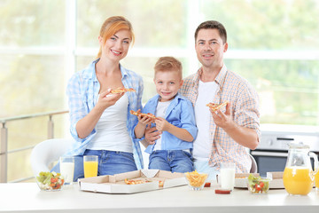 Happy family eating pizza in kitchen