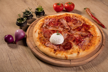 Pizza served on wooden board and raw ingredients on table