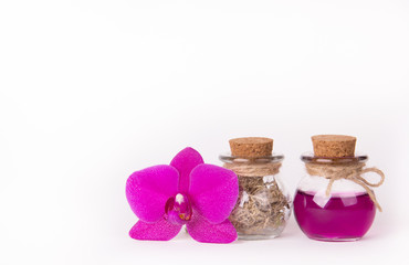 Fototapeta na wymiar Pink orchid and two glass bottles on a white background. Spa concept. Cosmetic bottles. Ecological natural cosmetics. Copy space.