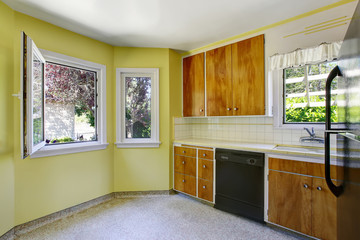 Small kitchen room interior with yellow walls, wooden cabinets and tile counter top.