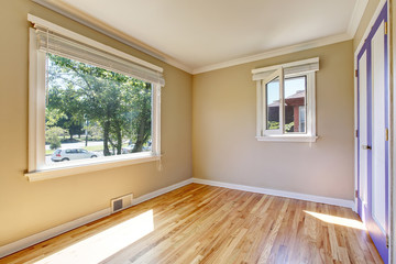 Empty room interior with polished hardwood floor and beige walls