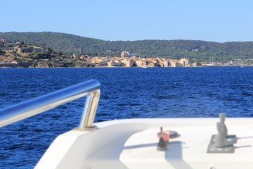 Distant view of Saint Tropez on the Mediterranean coast of France seen from an approaching ferry boat in blurred foreground