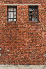 Old brick wall with boarded up Windows, abandoned building in decline