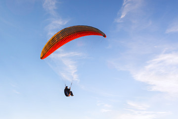 man flying on a paraglider against the evening blue sky.