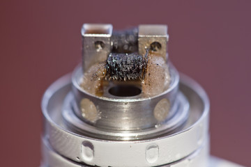 Macro photo of dirty twisted coil mounted in the electronic cigarette