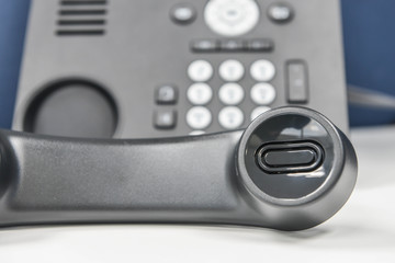 IP Phone handset is holding the call on the white table