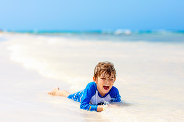 Fototapeta na wymiar little blond kid boy having fun on tropical beach of Jamaica