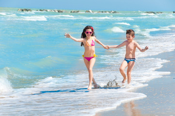 Children running on the beach holding hands