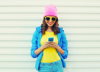 Fashion happy cool smiling girl using smartphone in colorful clo