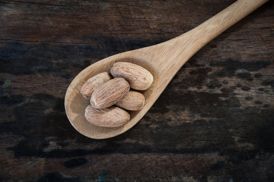 Nutmeg on wooden spoon over wooden background