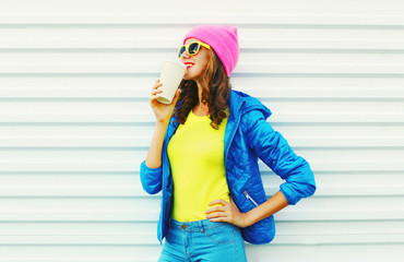 Fashion pretty woman with coffee cup in colorful clothes over wh