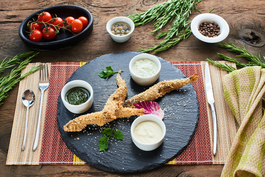Top view of the smelt, breaded with garlic tzatziki sauce and tomatoes on a stone Board
