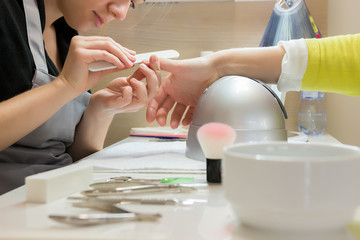 Manicurist woman is filing client's nails