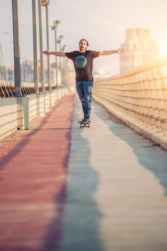 Skateboarder skates over a city bridge. Free ride street skateboarding