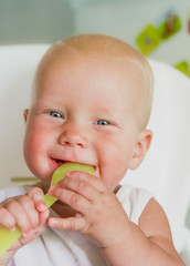 Portret of cute smiling baby  with a spoon in the high chair 