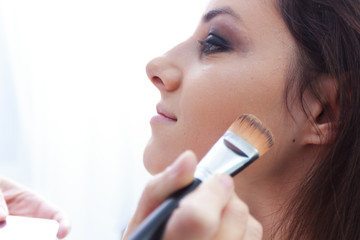 The power of make up,beautician woman applying professional make up to a beautiful young girl
