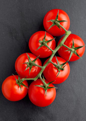Fresh organic tomatoes on black stone board