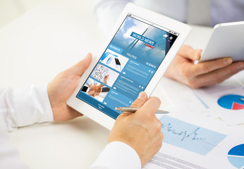 close up of hands with business news on tablet pc