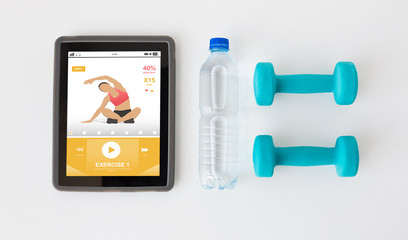 close up of tablet pc, dumbbells and water bottle