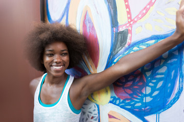 young happy and pretty afro woman laughing near old building