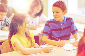 group of school kids writing test in classroom