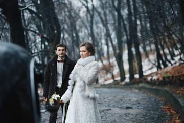 beautiful and happy newlyweds walking in rainy weather