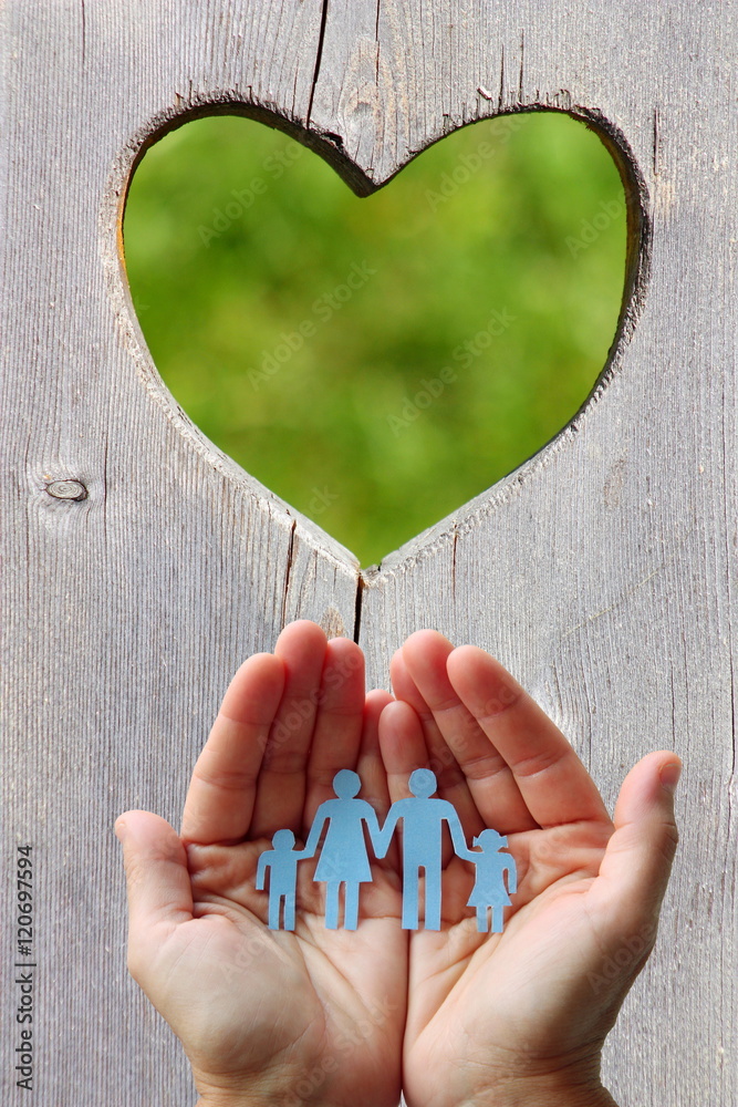 Wall mural Paper family in hands on wooden background with heart 