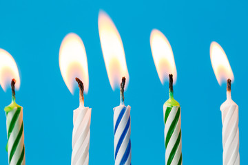 birthday candles burning over blue background