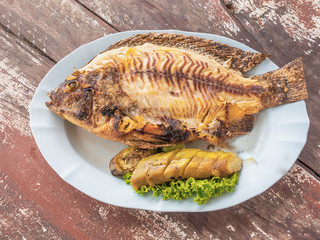Salt-Crusted Grilled Fish in a dish on the table, along with a side of eggplant baked ready to eat.