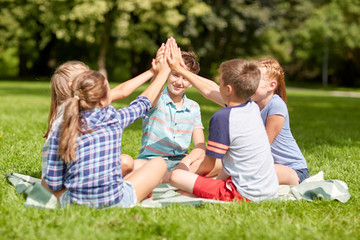 group of happy kids making high five outdoors