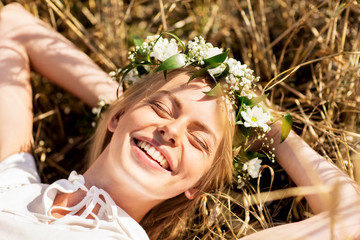 happy woman in wreath of flowers lying on straw