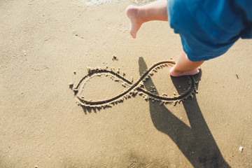 infinity symbol written on sand.