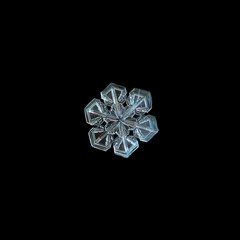 Snowflake isolated on black background. This is macro photo of real snow crystal with short broad arms and almost perfect symmetry.