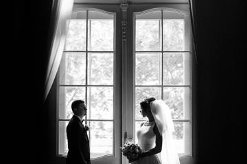 beautiful bride and groom standing together near a window