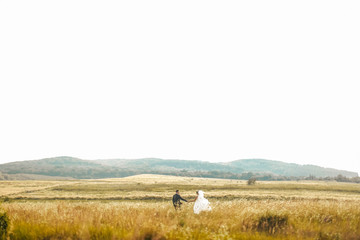 happy husband and wife walking together in field