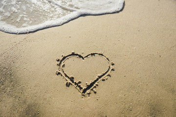 Fototapeta na wymiar Heart on the sand beach. Conceptual love