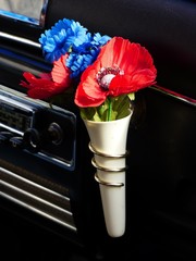 Rote und blaue Blumen in einer Vase am Armaturenbrett eines Auto der Wirtschaftswunder Ära und...