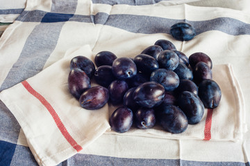 Ripe plums on textile napkins and rural tablecloth