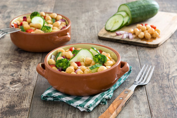 Chickpea salad in brown bowl on wooden background

