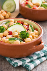 Chickpea salad in brown bowl on wooden background


