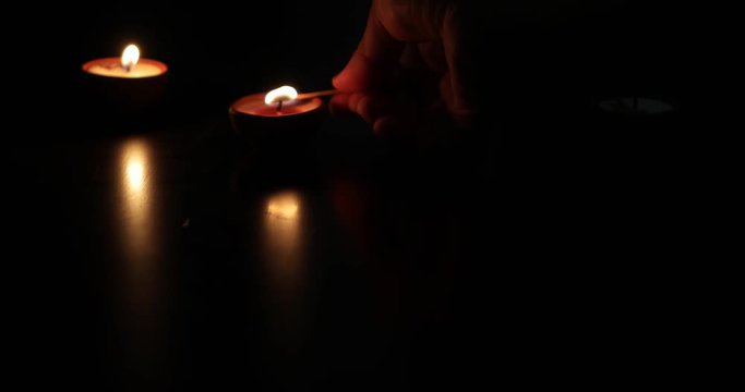 Human hand lighting up four 4 Traditional clay diya lamps lit during Diwali celebration with a matchstick 