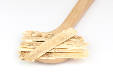 Chinese Herbal medicine - Astragalus slices, Huang Qi (Astragalus propinquus) on wooden spoon over white background