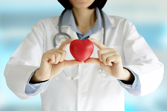 Positive female doctor standing with stethoscope and red heart s
