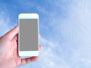 Left-hand holds the smartphone grey screen with sky background behind