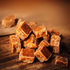 Caramel candies on brown background. Salted caramel pieces and s