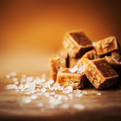 Caramel candies on brown background. Salted caramel pieces and s