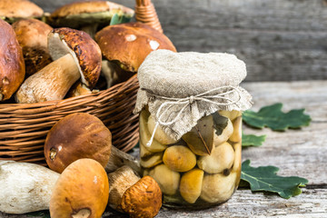 Boletus mushrooms marinated in jar on rustic wooden table