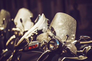Scooters are parked on the city street at dusk, in Rome, Italy