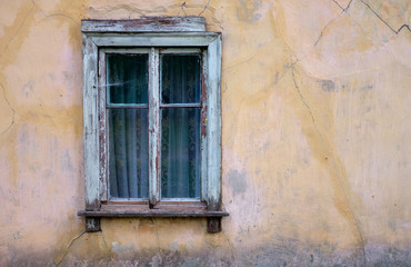 Ветхое деревянное окно со шторами  старого обветшавшего жилого дома 